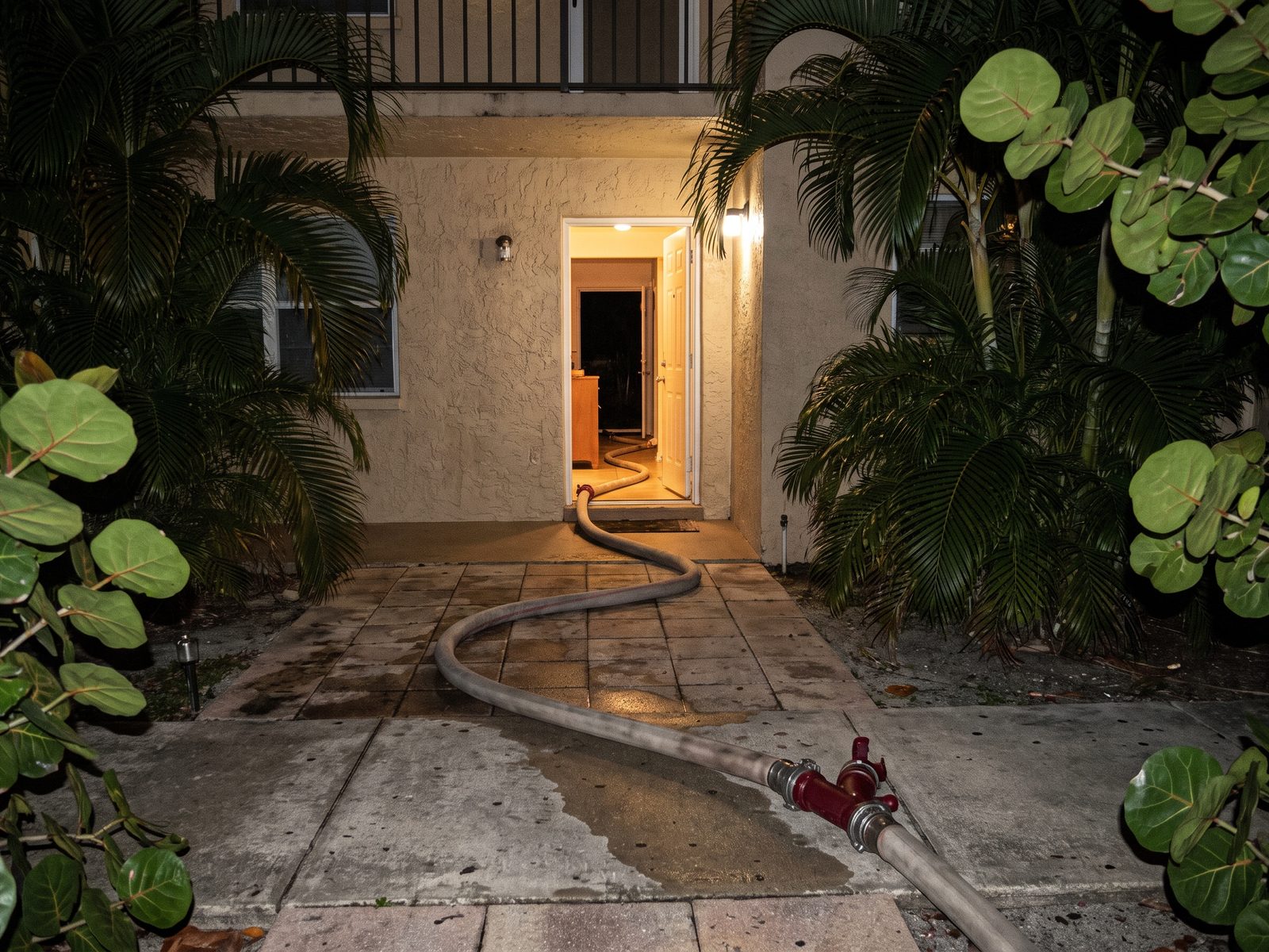 Night Mobilization Miami Beach | Restoration Doctor Extraction hose run through a doorway into a ground-floor South Florida unit during a night response.