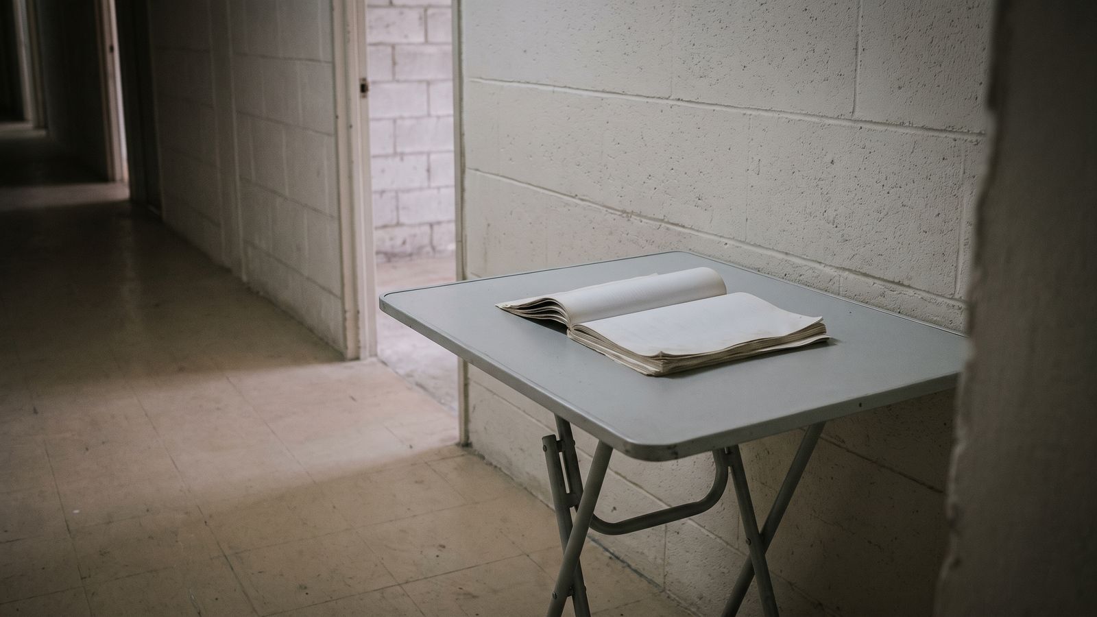 Where a Condo Rebuild Is Decided A fanned document set open on a folding table in a bare block-wall condominium corridor