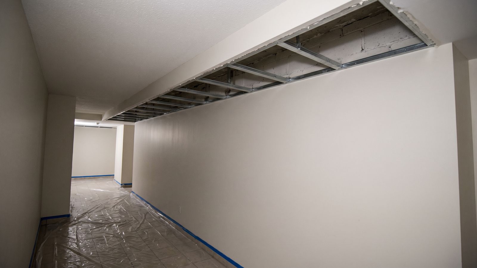 Opened Soffit in a Common Corridor A common corridor ceiling opened along a soffit with metal furring exposed and the floor sheeted below