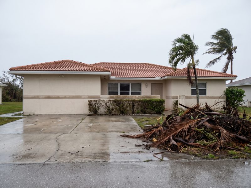 Ground-level South Florida house on a slab with a visible water line on the stucco after flooding.