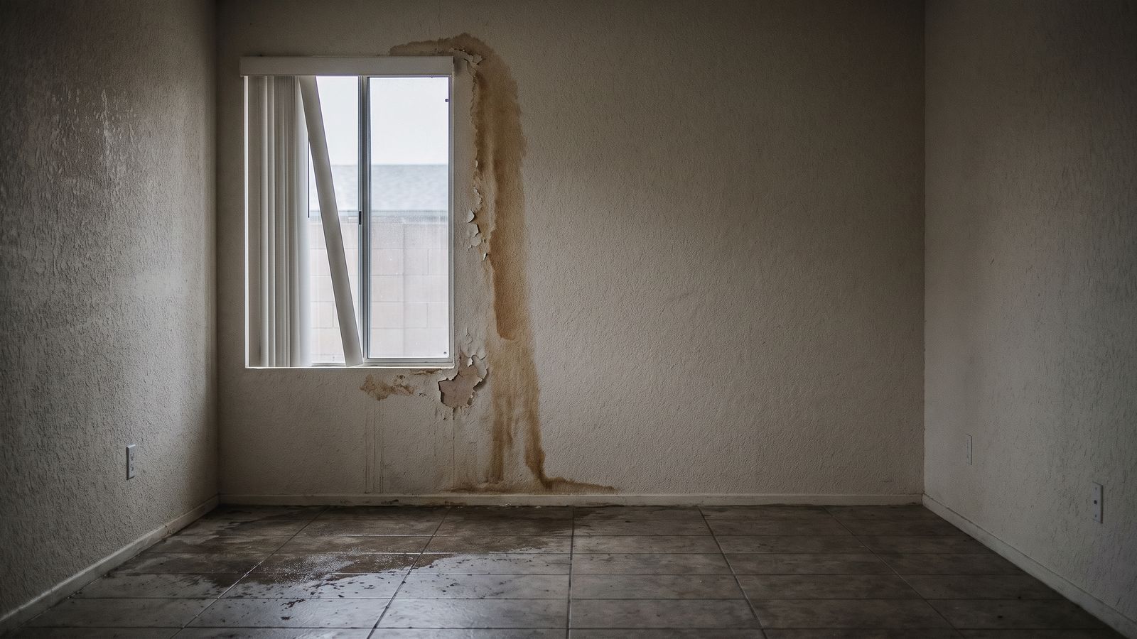 Wind-driven rain track down a stucco wall to wet tile Wind-driven rain staining down an interior stucco wall from a window head onto wet tile in a South Florida living room