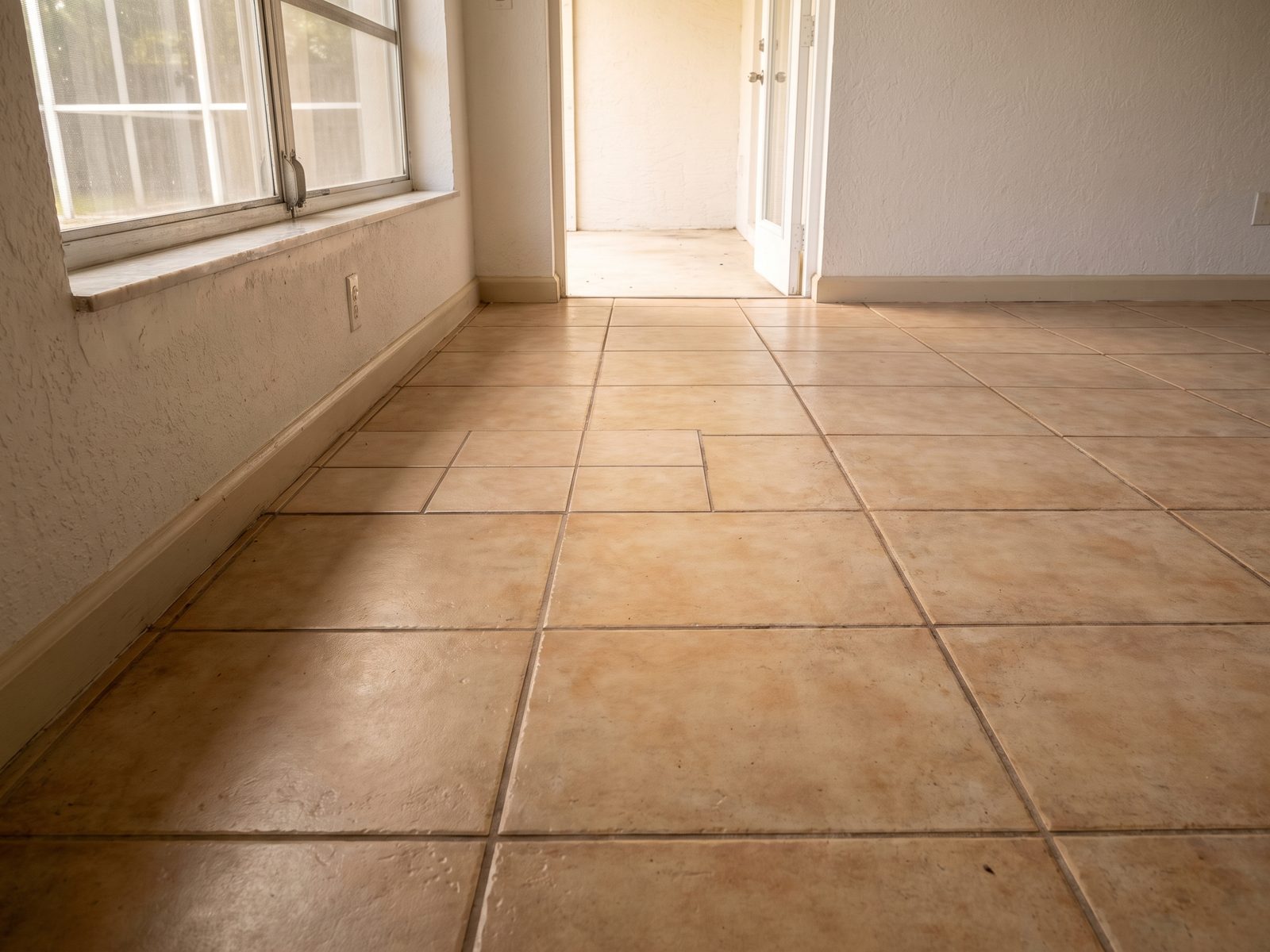 Shade Mismatch in a Tile Repair | Restoration Doctor Low view along a tile floor where a patch of replacement tiles breaks the pattern and tone of the original field.