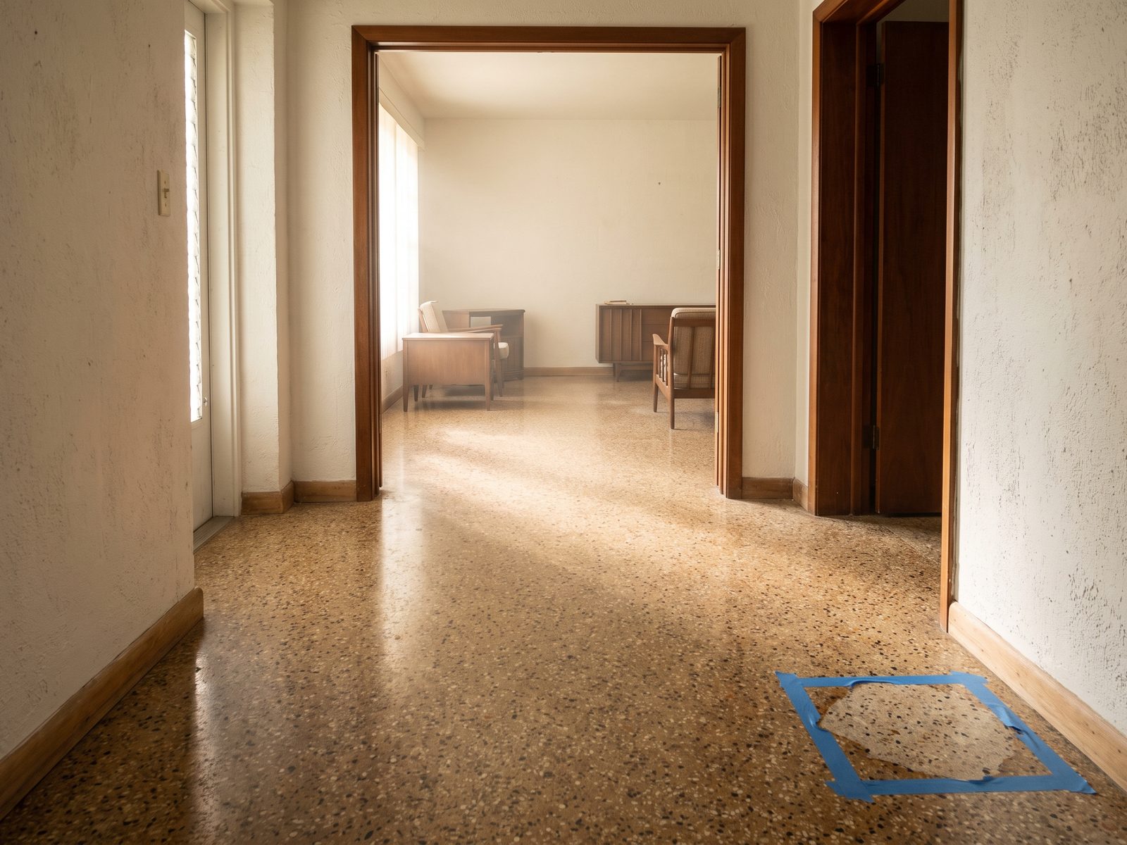 Continuous terrazzo flooring running from a hallway into a living room in a mid-century Coral Gables home.