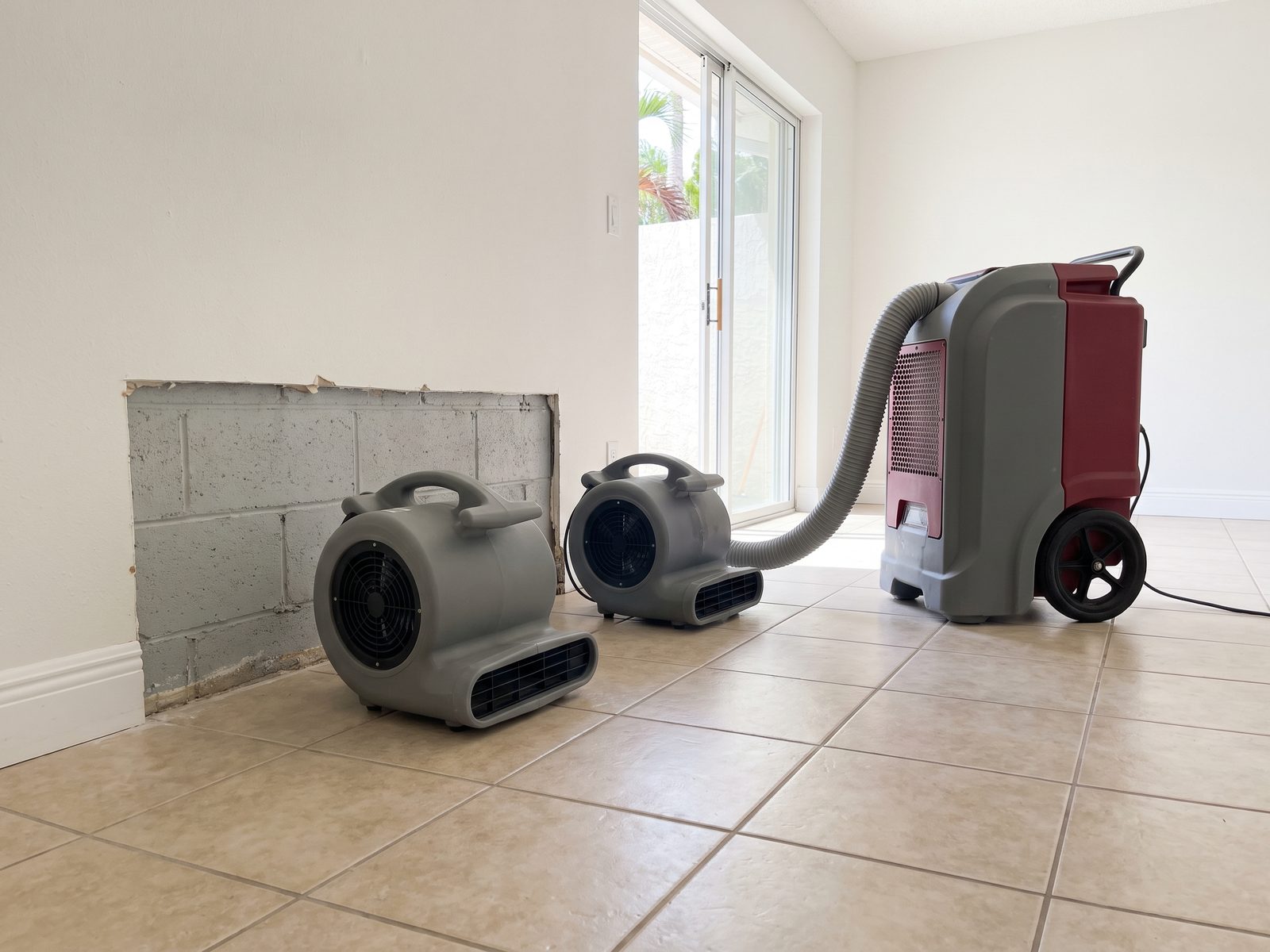Drying Equipment in a South Florida Room | Restoration Doctor Air movers and a dehumidifier running against a bare block wall in a tiled South Florida room.
