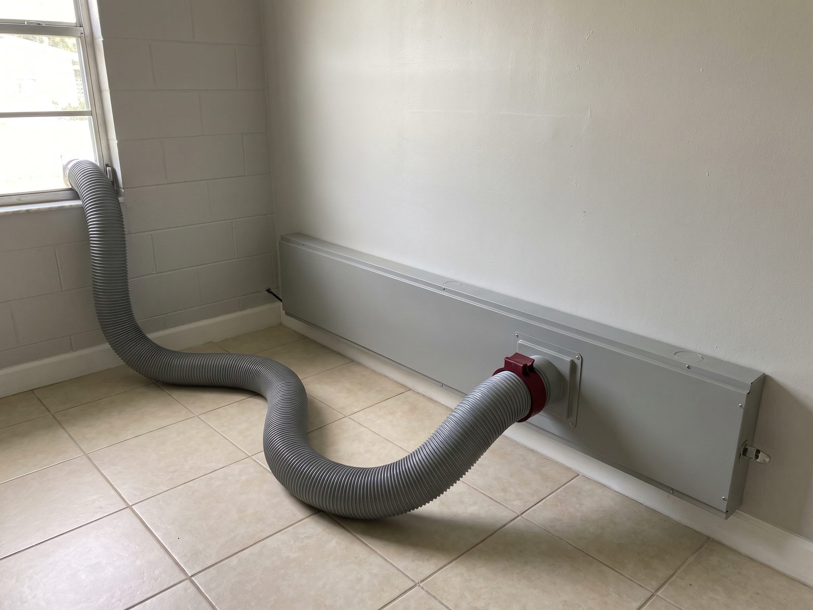 Injection Drying Setup Florida | Restoration Doctor Flexible drying hose clipped into a wall-cavity injection panel along a baseboard line in a Florida home.