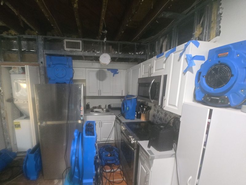 Air movers and other drying equipment set in a kitchen with opened walls and an open ceiling in a Miami Beach, FL unit, January 2026, Restoration Doctor project documentation.