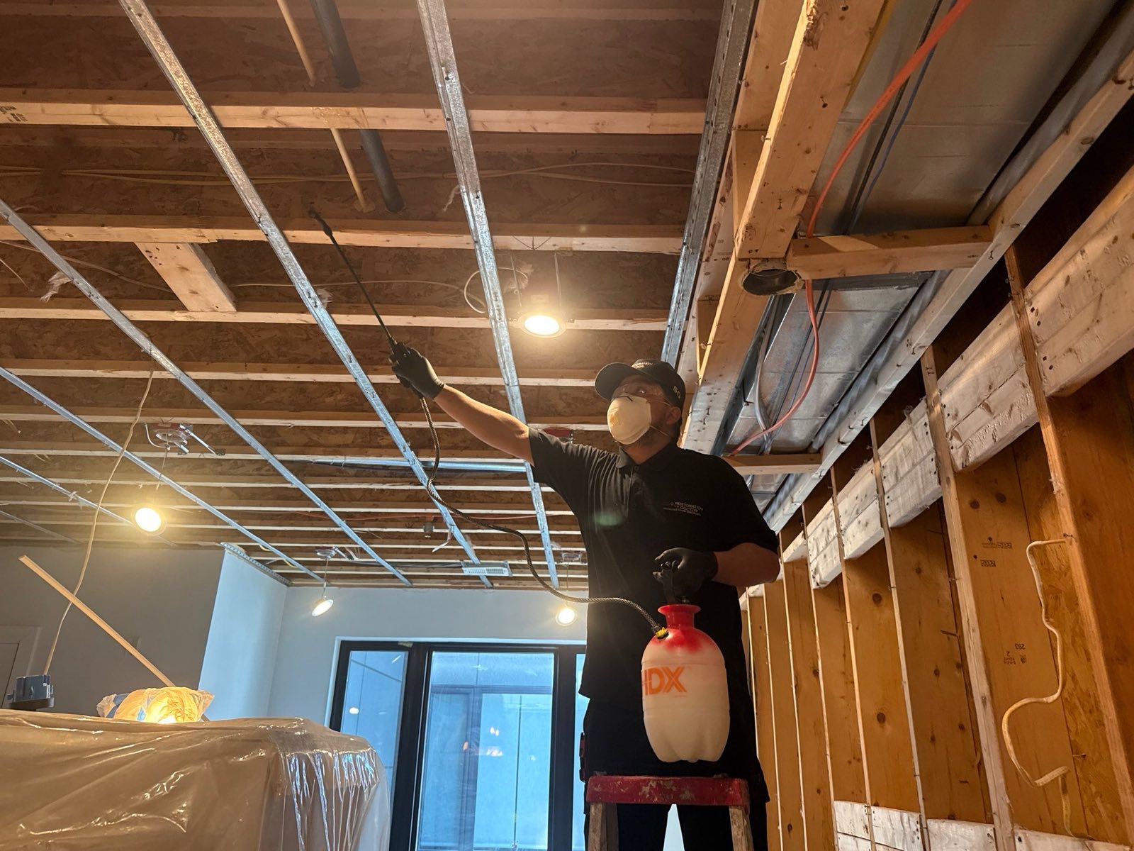Restoration Doctor technician treating exposed ceiling framing during water damage demolition